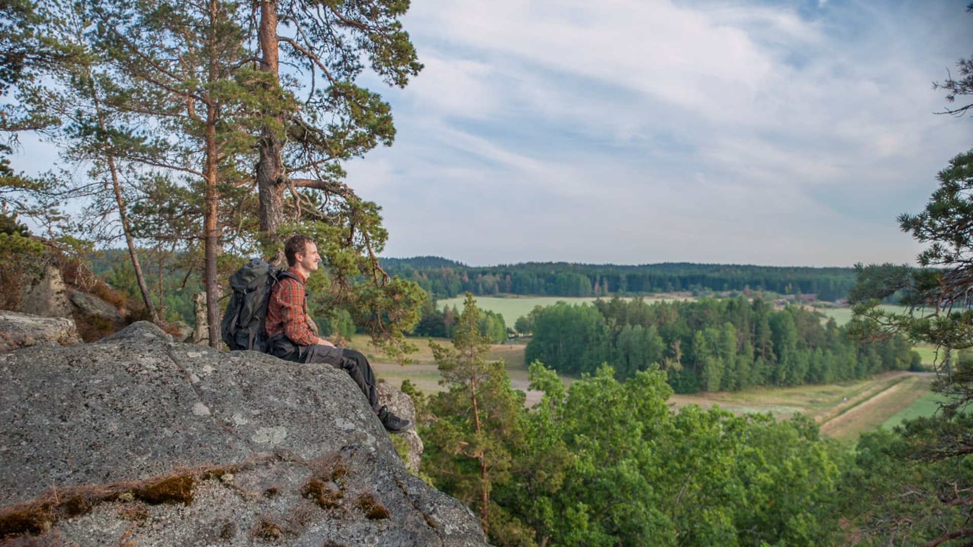 Man som sitter på Simonberget och blickar ut