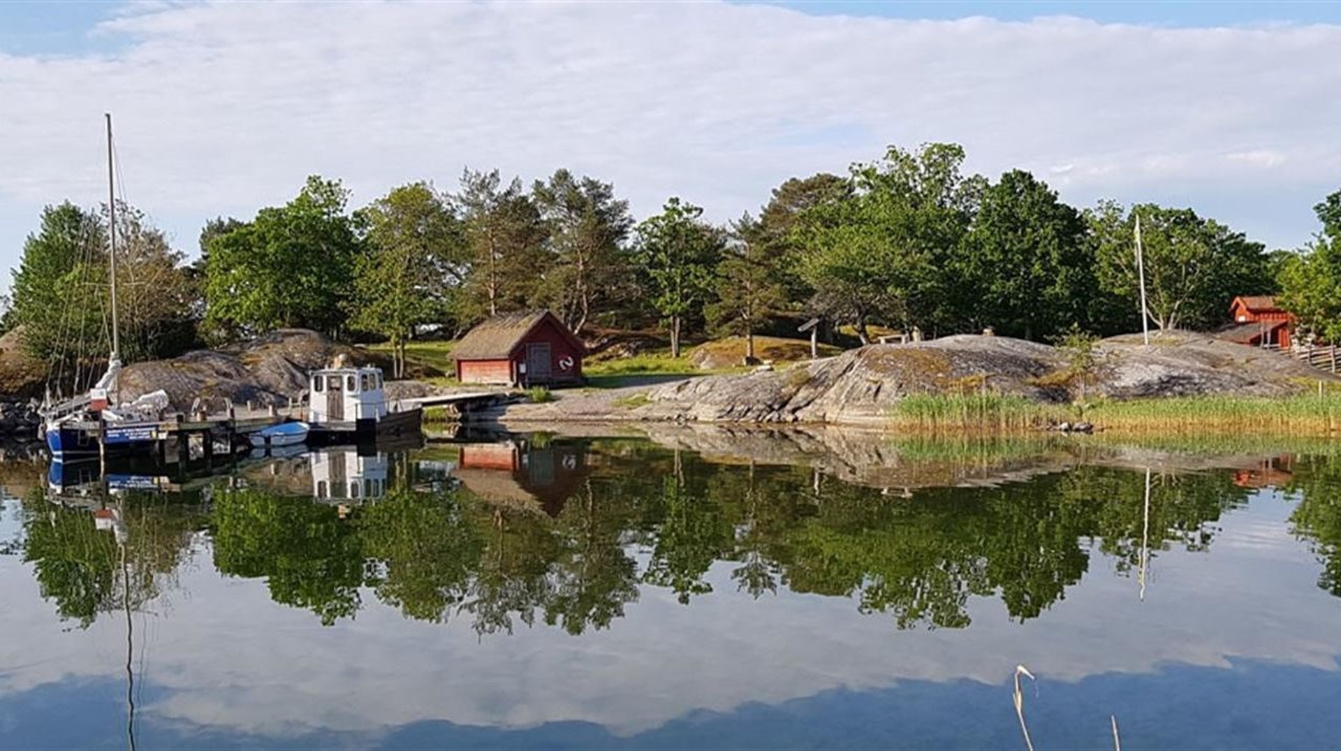 En ö med brygga och båtar en sommardag
