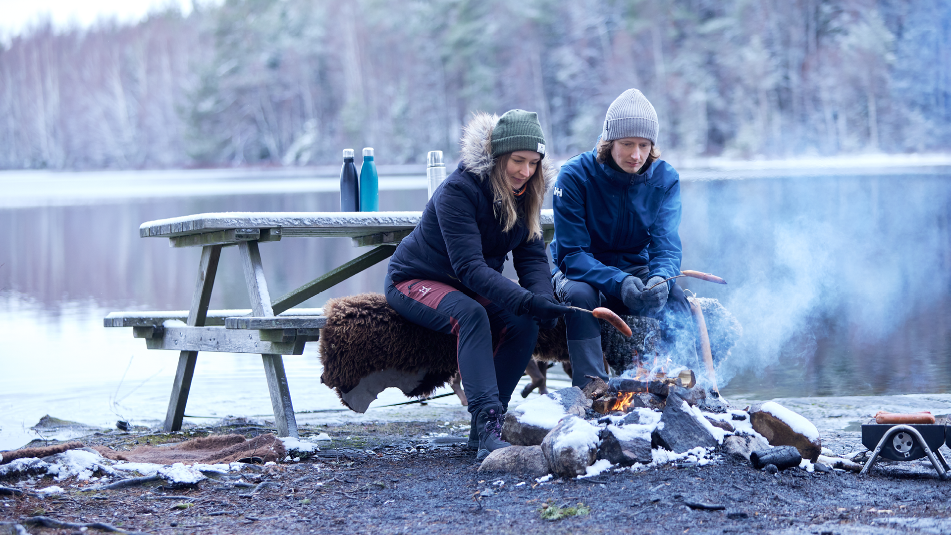Två personer som grillar korv under vintern.